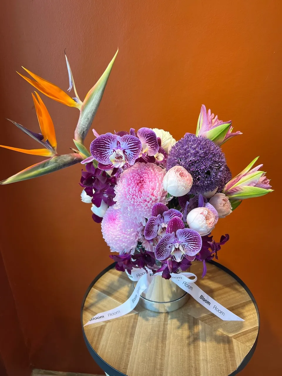 Striking arrangement with striped orchids, birds of paradise and purple allium