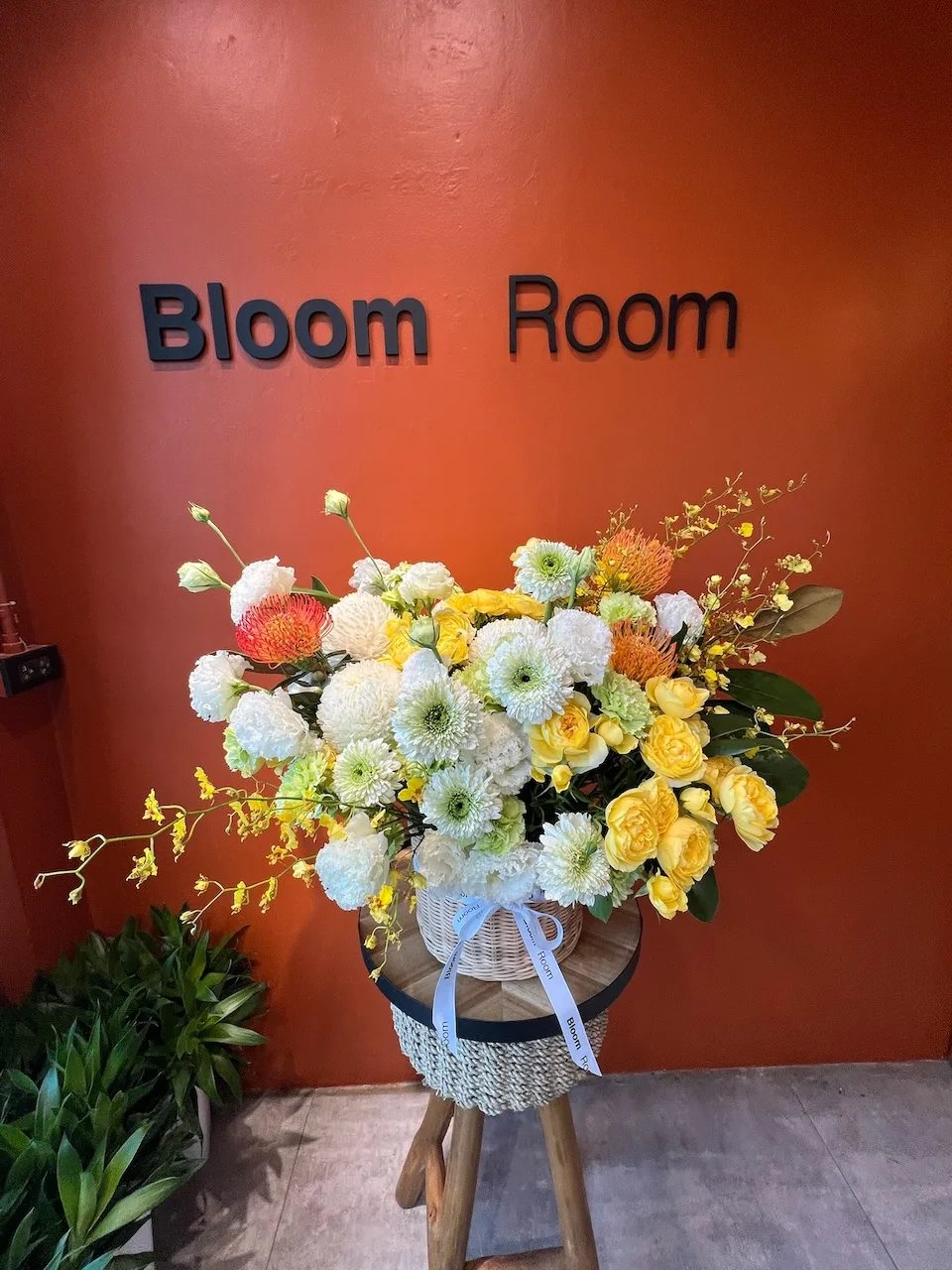 Tall stand arrangement with yellow and white chrysanthemums, oncidium orchids, orange gerberas and ranunculus