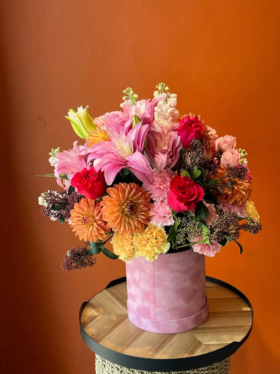 Vibrant pink hatbox with lilies, dahlias, roses and snapdragons